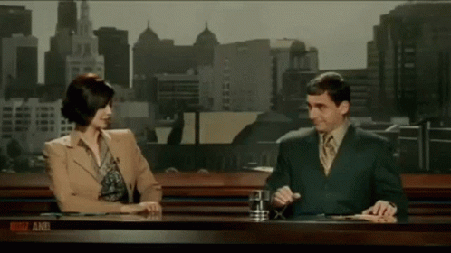 man and woman sitting down talking in an newscast