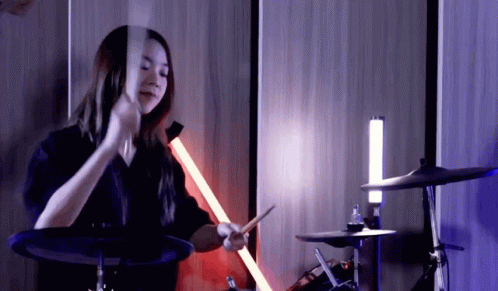 a young woman is holding a sword in front of her drums