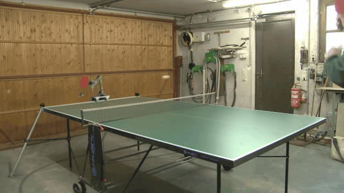 a ping pong table is on the floor of a garage