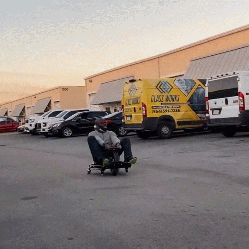 a person on a skateboard sitting in a parking lot with many vehicles