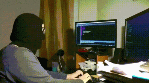 the man has a hood on working in his computer