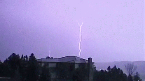 lightning striking in pink sky over a small town