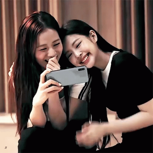 two girls smiling and holding onto an open tablet