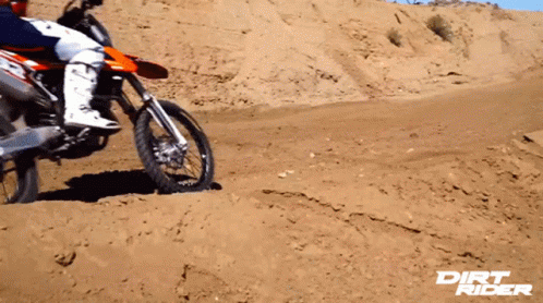 a man riding a dirt bike over a sandy hillside