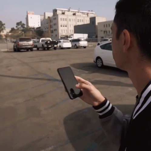 a  playing with a small screen in the parking lot