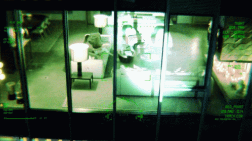two people inside of a glass fridge and another person on the other side with a laptop