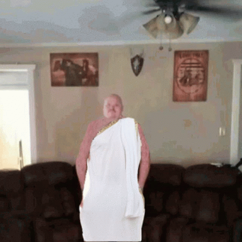 a man standing in a living room with a big white towel on his shoulders