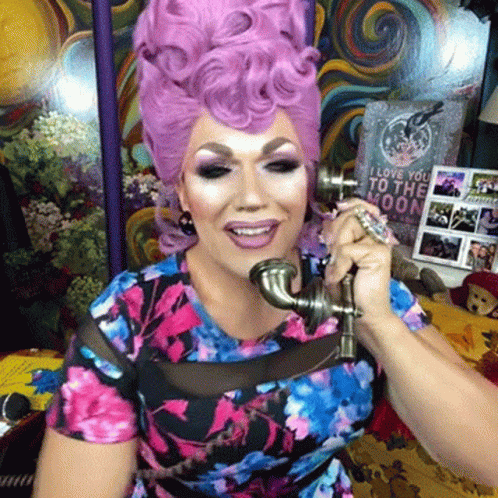 a woman with an ugly pink wig holding a silver object in front of her face