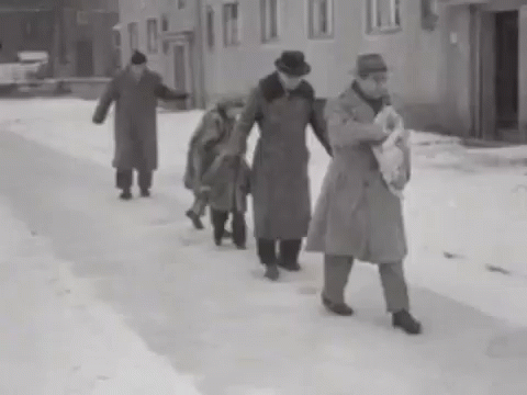 a woman in trench coat walking through snow with two children
