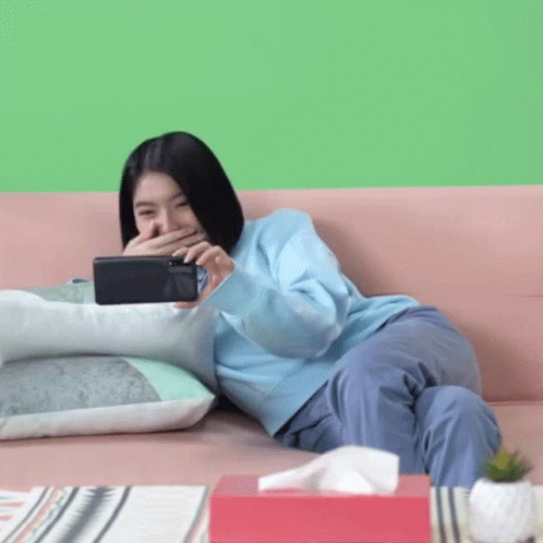 the young lady is laying on a couch using a tablet computer