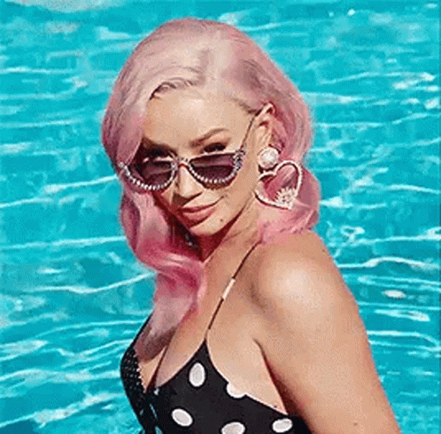a lady with sunglasses is sitting next to a body of water