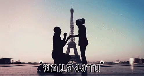 a woman handing soing to a child standing on the ground in front of the eiffel tower