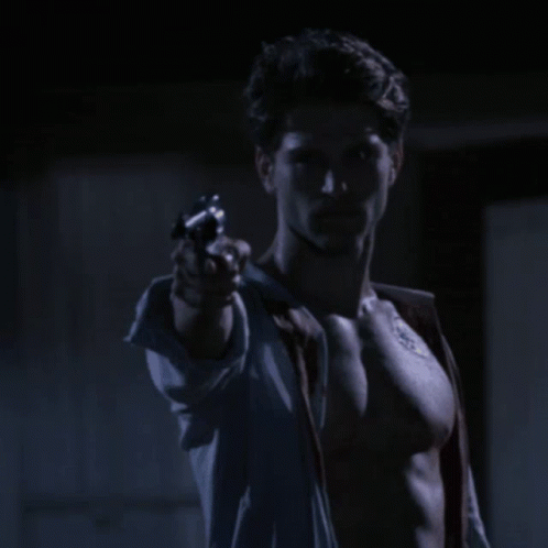 a shirtless man holding a gun in his right hand