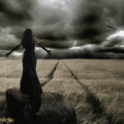 woman in an open field in dark with stormy skies above