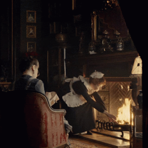 two people sit and look at the fireplace in a dimly lit room