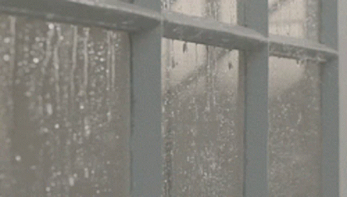 rain coming down a window, and water drops running down the windowsill