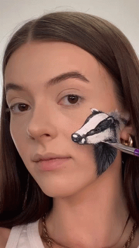 a young woman holding a piece of paint to her face