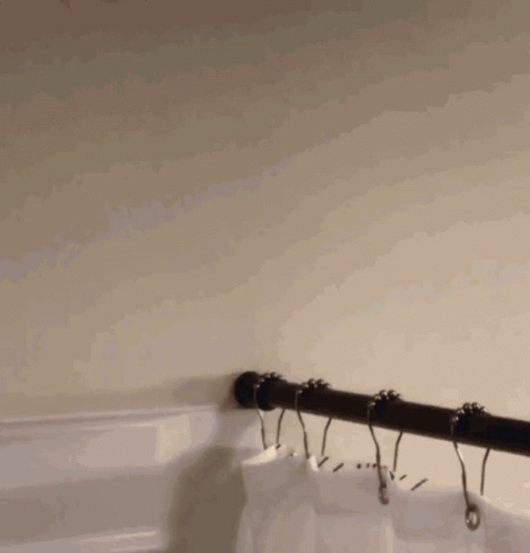 a black pipe hanging from a wall with some hooks