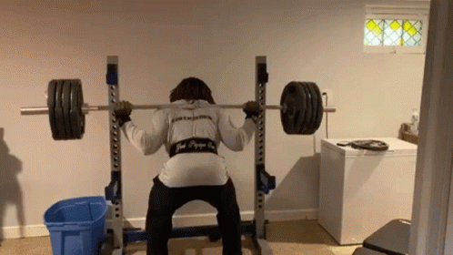 a woman is in the gym squatting down with a barbell