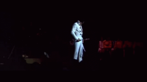 a person dressed in white walking at night on stage