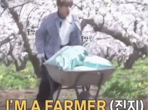 man hing wheelbarrow with large bag, saying'i'm a farmer '