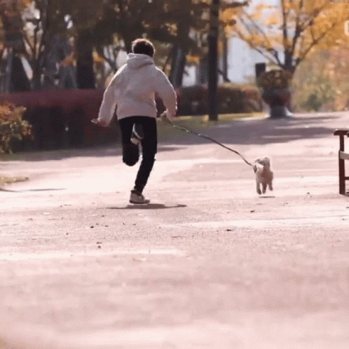man in a white coat pulling his dog on a leash