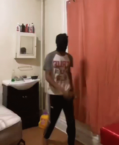 a man standing in a bathroom taking a shower curtain