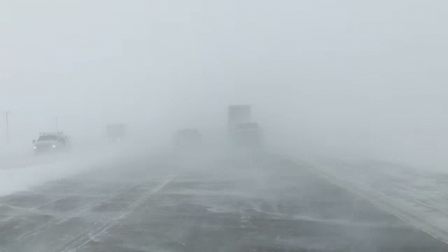 a truck travels on the snow and fog with trucks driving in distance