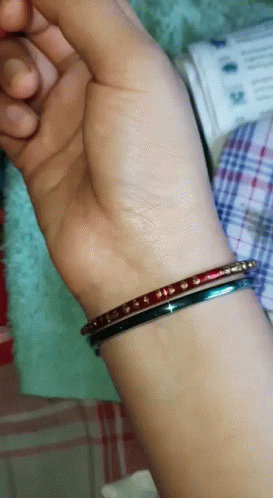 a person with a purple wrist wearing a gold celet