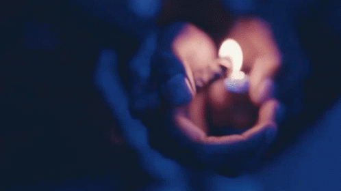 a close up of someone holding a small lit candle