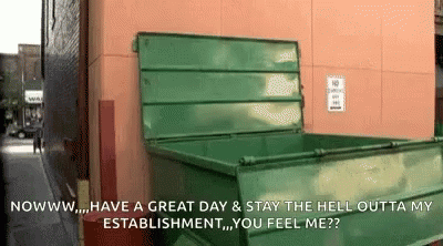 a green metal bin sitting in front of a blue wall