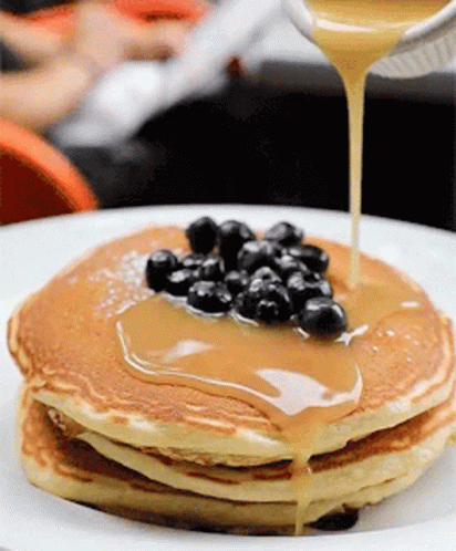 blue pancakes are sitting on a plate with blue powder and black berries