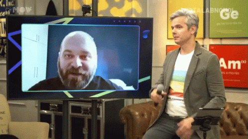 a man standing in front of a flat screen tv with a picture of a man sitting on it