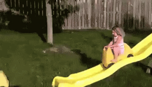 a child sliding down a small slide on a lawn