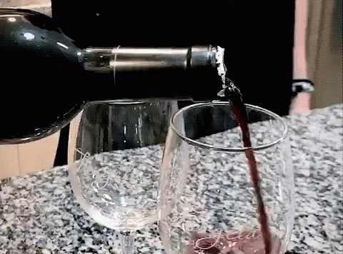 wine pouring into glass from bottle onto granite counter top
