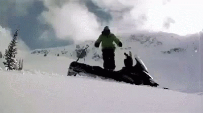 a skier standing next to a person on a snow mobile