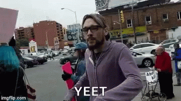 this is a man on a city street with a sign that says yeet