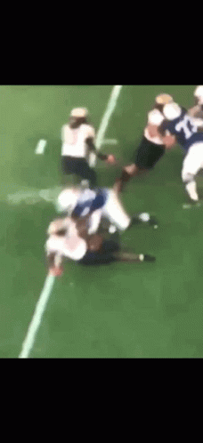 a football player in white jersey gets tackled by teammates