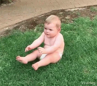 a baby is sitting on the grass by himself