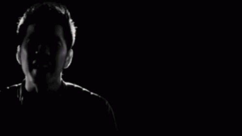man is singing into his microphone in the dark