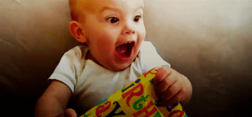an infant is laughing and opening a box with its mouth wide open