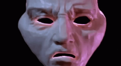 an alien mask looks at soing with a purple glow