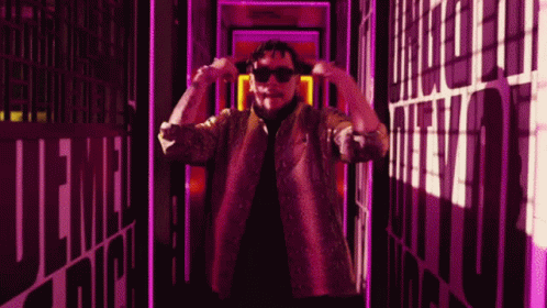 a man is holding his sunglasses in one hand and standing in the middle of a hallway