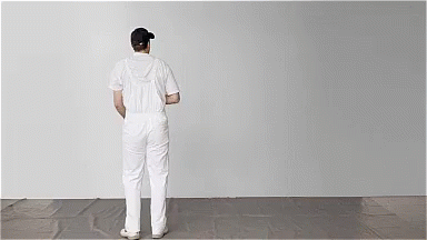 a person is standing in front of a white wall and painting