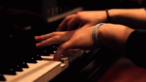 two hands playing an electric piano in the dark