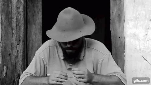 a man wearing a hat is looking down at his hands