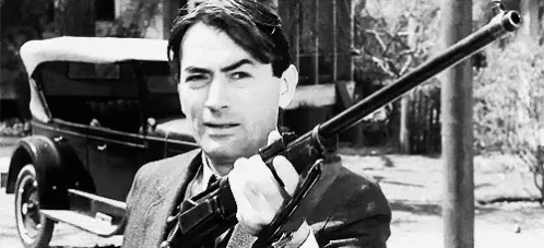 black and white pograph of man in suit with gun
