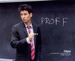 a man standing in front of a blackboard while pointing to it