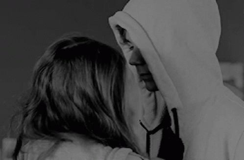 two people, one in a hooded jacket, are looking at each other and touching