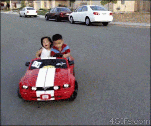 a  rides a toy car and a man is driving it